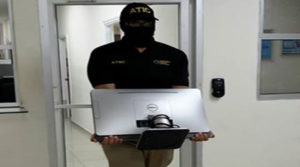 Un agente de la ATIC carga una computadora portátil que supuestamente contiene información de policías corruptos.